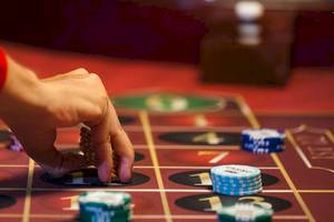 Eine Person spielt an einem Casino-Tisch mit verschiedenen Spielchips und Spielmarken.