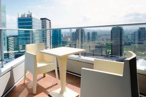 Terrasse mit weißen Stühlen und Tisch, Blick auf die Stadt mit hohen Gebäuden.