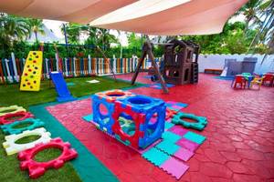 Spielplatz des Catalonia Bayahibe Hotels mit Rutsche, Kletterwand und bunten Spielsachen.