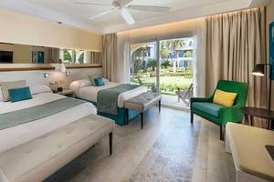 Doppelzimmer im Catalonia Bayahibe Hotel mit zwei Betten, großer Terrasse und Gartenblick.
