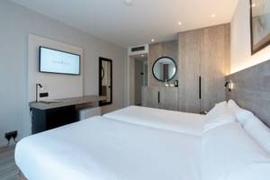 Ein Schlafzimmer im Attica 21 Barcelona Mar Hotel mit zwei Betten, einem Fernseher und einem Schreibtisch.