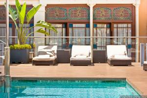 Pool-Lounge-Sessel vor dem Grupotel Gran Via 678 mit blauen Fenstern und Pflanzen.