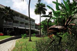 Außenansicht des La Pagerie - Tropical Garden Hotel mit gepflegtem Garten und Flamingoskulptur.