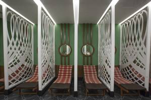 Innenbereich der Saunalounge im Azura Deluxe Resort & Spa mit roten und weißen Sitzbänken, weißen Gitterwänden und grünen Wänden.