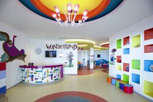 Kinderbereich im Azura Deluxe Resort & Spa mit bunten Wandmalereien, einem Empfangstresen und einer Regenbogendecke.
