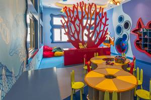 Kinderzimmer im Güral Premier Belek Hotel mit bunten Möbeln, blauen Wänden und einem roten Korallen-Dekor.