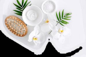 Gesichtspflegeprodukte wie eine Creme, Salz und Blüten auf weißem Hintergrund