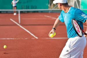Tennisspieler spielt auf einem roten Tennisplatz während eines Matches.