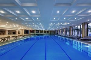 Innenpool des Delphin Deluxe Hotels mit Loungebereich und Sonnenliegen