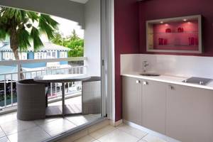 Balkonküche im La Pagerie - Tropical Garden Hotel mit Tisch, Stühlen und Blick auf Palmen und Gebäude.