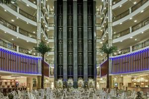 Foyer des Delphin Deluxe Hotels mit vielen Tischen und Stühlen, hohen Säulen und blauen Lichtern.