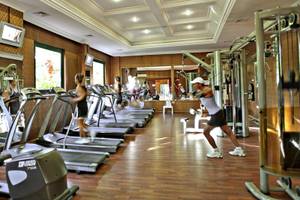Fitnesscenter im Delphin Deluxe Hotel mit Läufern auf Laufbändern und einem Mann, der an einem Zugapparat arbeitet.