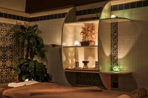 Spa Behandlungsraum im Delphin Deluxe Hotel mit Massageliege, Pflanzen und dekorativen Elementen.