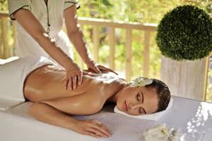 Eine Frau genießt eine Massage auf einer Liege im Delphin Deluxe Hotel.