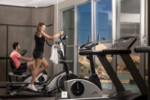 Fitnesscenter im Melas Holiday Village mit Frau auf dem Crosstrainer und Mann auf dem Rudergerät.