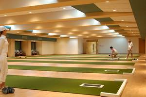 Innenansicht der Bowlingbahn im Constantinou Bros Athena Beach Hotel mit Spielern und Holzböden.