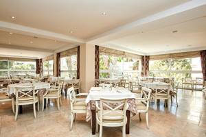 Innenansicht des Restaurants im Beach Club Font de Sa Cala mit mehreren Tischen und Stühlen.