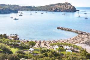 Aussicht auf das Cape Sounio Grecotel Resort mit vielen Booten im Wasser und Sonnenschirmen am Strand.