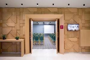 Konferenzraum im Dolce Athens Attica Riviera Hotel mit Holzwänden und grünen Stühlen.