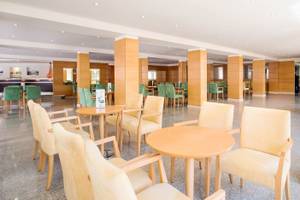 Innenbereich des La Santa Maria Playa Hotels mit hellen Holzmöbeln und grünen Stühlen.