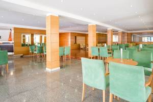 Innenbereich des Restaurants im La Santa Maria Playa Hotel mit grünen Stühlen und Holztischen.