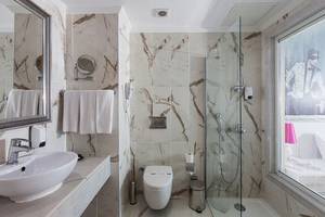Badezimmer des Sultan of Dreams Hotels mit Marmorwänden, Dusche, Toilette, Waschbecken und Spiegeln.