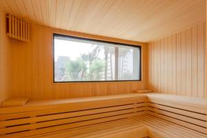Innenansicht der Sauna im Aparthotel Marins Playa mit Holzwänden und einer großen Fensterscheibe.