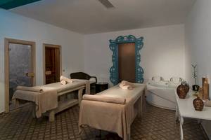 Spa-Behandlungszimmer im Sultan of Dreams Hotel mit zwei Massagetischen und einer Badewanne.