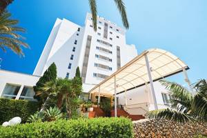 Außenansicht des Hipotels Don Juan Hotels mit weißem Gebäude und tropischen Pflanzen.