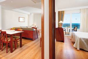 Innenansicht des Hipotels Dunas Cala Millor Hotels mit Esstisch, Sofa und Meerblick