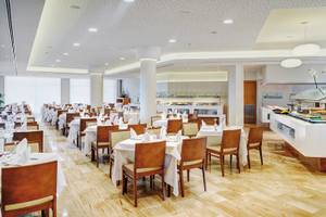 Restaurant im Hipotels Dunas Cala Millor mit gedeckten Tischen und Buffet.