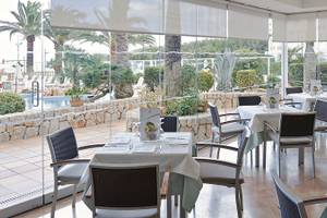Restaurant im Hipotels Dunas Cala Millor mit großen Glaswänden und Blick auf den Pool.