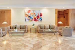 Hotellobby von Hipotels Dunas Cala Millor mit Sofas, Tischen und Gemälden.