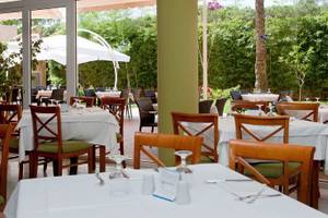 Gartenrestaurant im Bakour Garbi Cala Millor Hotel mit Tischen und Stühlen unter weißen Sonnenschirmen.