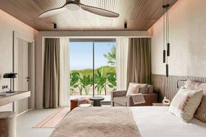 Schlafzimmer im Aldiana Club Side Beach Hotel mit großem Bett, Fenster und Aussicht auf die Natur.