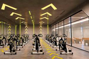 Fitnessstudio im Aldiana Club Side Beach mit vielen Spinrädern und gelben Lichtakzenten an der Decke.