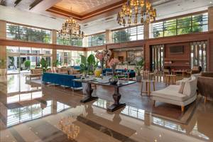 Lobby des Sherwood Exclusive Kemer Hotels mit blauen Sofas, einem Tisch und Kronleuchtern.