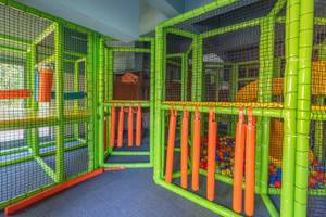 Kinderspielplatz im Sherwood Exclusive Kemer Hotel mit grünen und orangefarbenen Strukturen und Netzen.