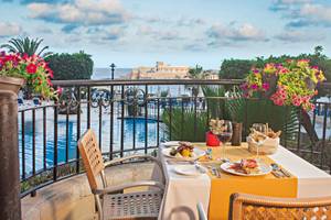 Terrasse im Corinthia St George's Bay Hotel mit Blick auf den Pool und das Meer