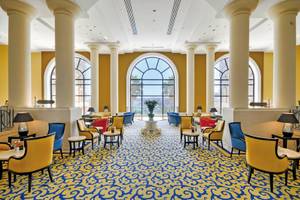 Lobby des Corinthia St. George's Bay Hotels mit gelben und blauen Mustern und großen Fenstern.