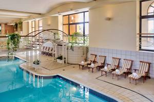 Innenpool im Corinthia St. George's Bay Hotel mit Sonnenliegen und Treppen.