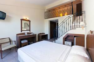Zimmer im Süral Garden Hotel mit Bett, Schreibtisch, Spiegel und Fernseher.