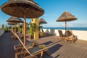Dachterrasse des Hovima Jardin Caleta Hotels mit Liegen, Sonnenschirmen und Meerblick.