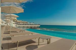Pool-Terrasse des RH Bayren & Spa Hotels mit Sonnenliegen und Sonnenschirmen am Meer