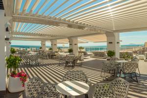 Terrasse des RH Bayren & Spa mit Sonnenliegen und Sonnenschirmen am Meer