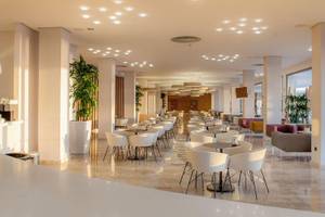 Hotel RH Bayren & Spa mit geräumiger Lobby, runden Tischen und Stühlen, Pflanzen und moderner Inneneinrichtung.