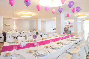 Bankettsaal im RH Bayren & Spa mit mehreren pinken und lilafarbenen Ballons, gedecktem Tisch und weißen Stühlen.