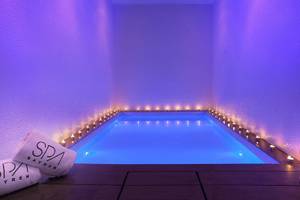 Innenpool des RH Bayren & Spa mit blauer Beleuchtung und brennenden Kerzen