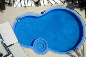 Luftaufnahme des Schwimmbeckens mit weißen Liegen und blauem Wasser im Principal Afilliated by RH.