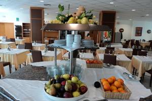 Ein Buffettisch in einem Restaurant mit einer Auswahl an Obst, Getränken und Geschirr.